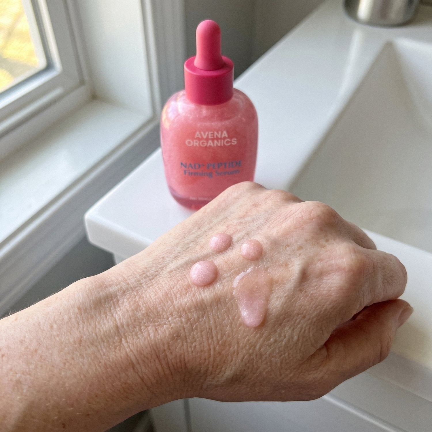 Drops of Avena NAD+ Peptide Serum on the back of a hand