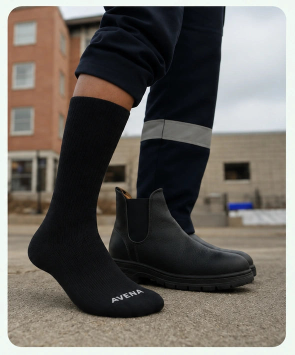 Black Avena compression sock worn outdoors beside a work boot