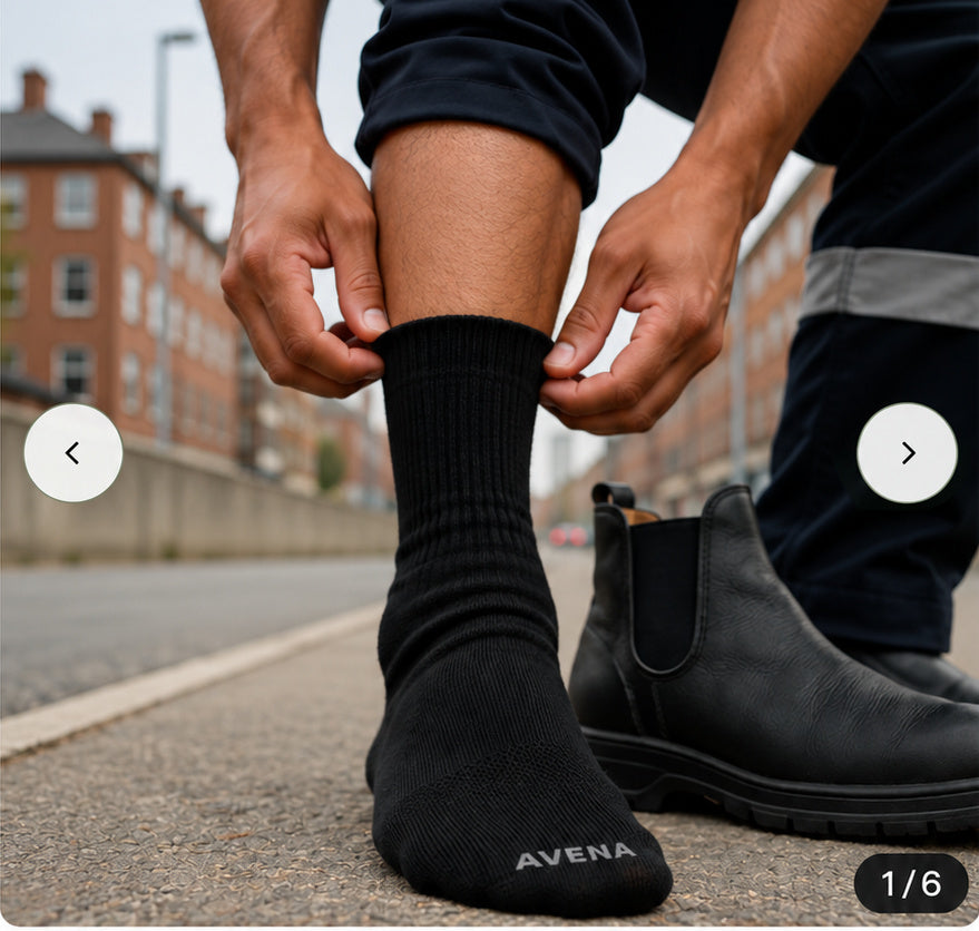 Person pulling on a black Avena toe sock beside a brick street