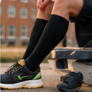 Black compression socks worn with green shoes