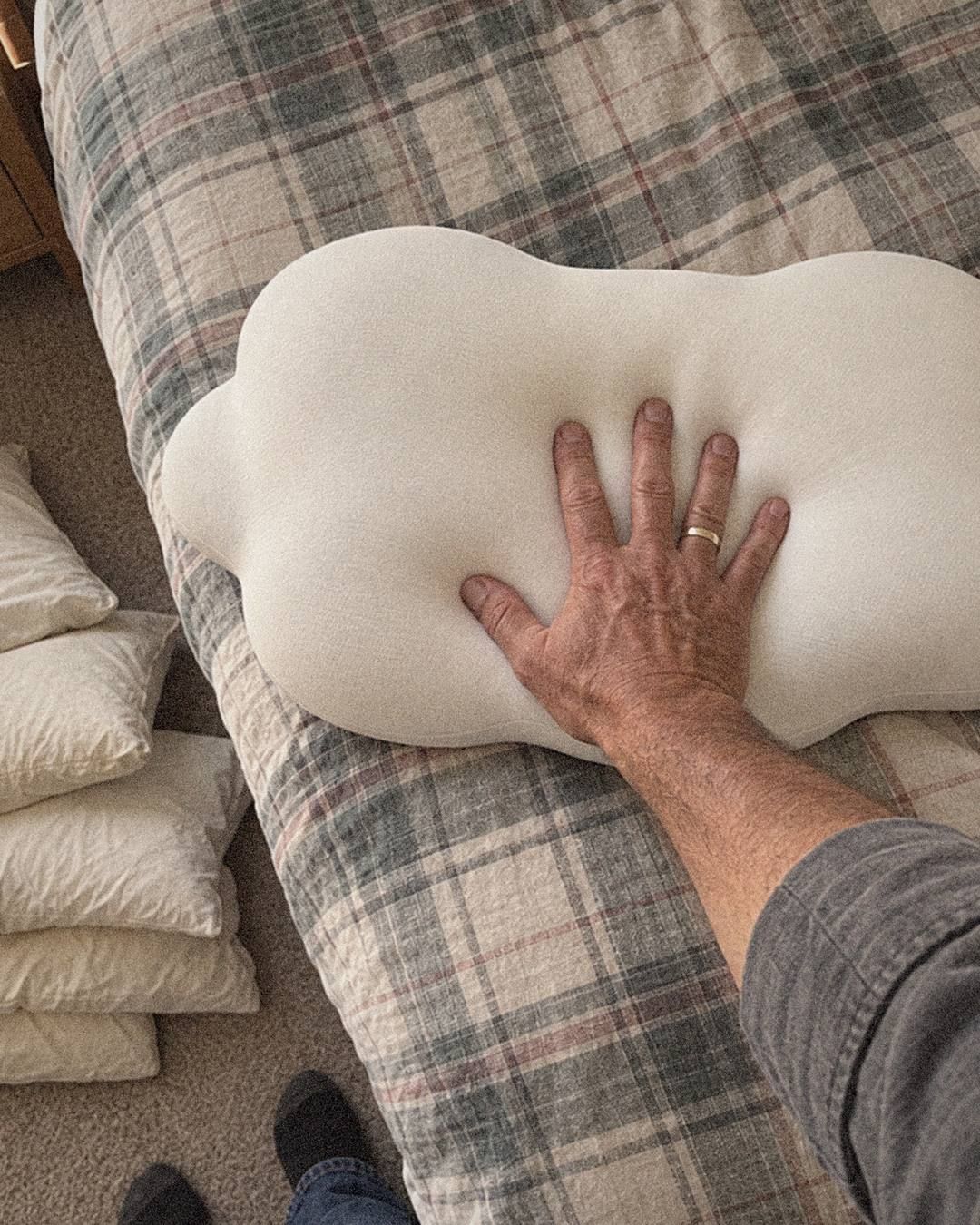 Wes pressing into his Cloud Pillow, with his old flat pillows stacked on the floor