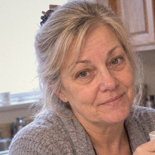 Linda M. at her kitchen table with a mug of coffee