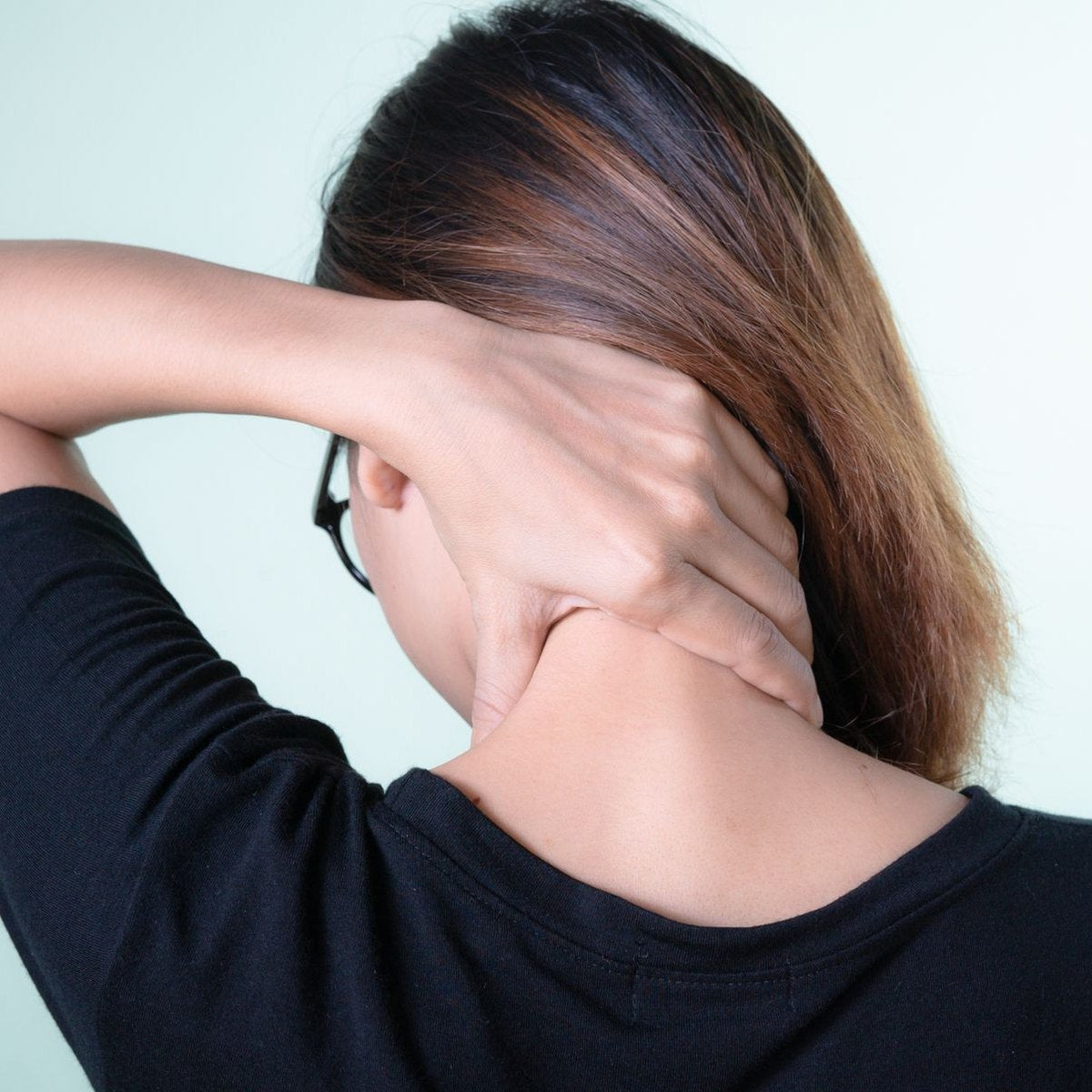 Woman holding the back of her stiff neck