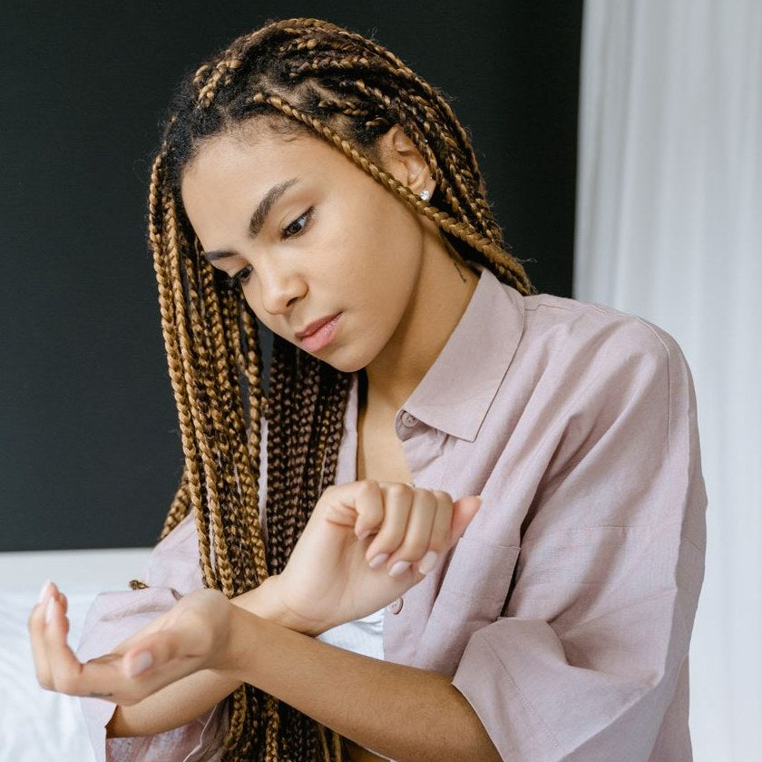 Woman sitting on her bed in the morning, holding her sore wrist